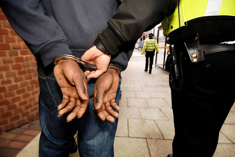 man in handcuffs being pulled by police